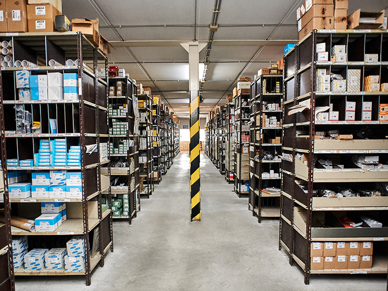 Un magazzino pieno di scaffali e scatole, che immagazzina vari articoli a scopo di distribuzione e stoccaggio.